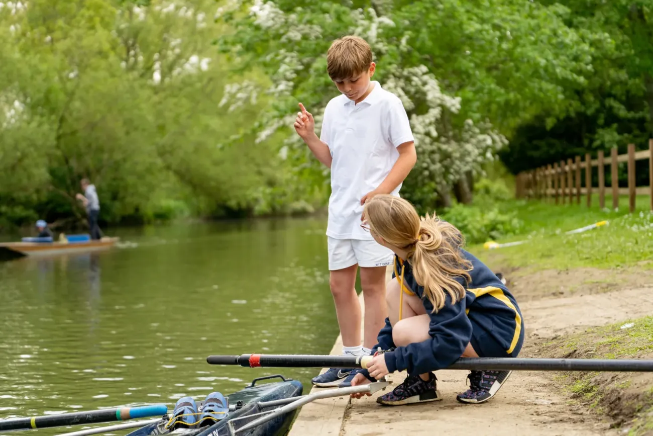 Children preparing rowing equipment riverside