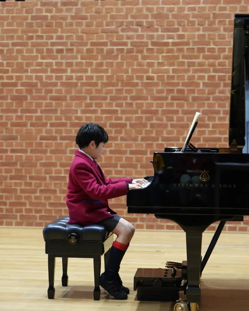 Junior pupil performing on Steinway grand piano