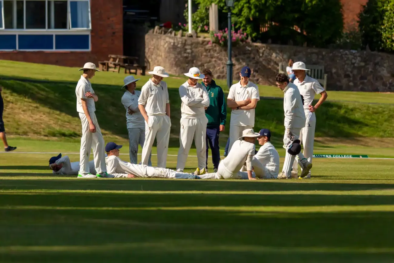 Cricket team gathered on sunlit pitch