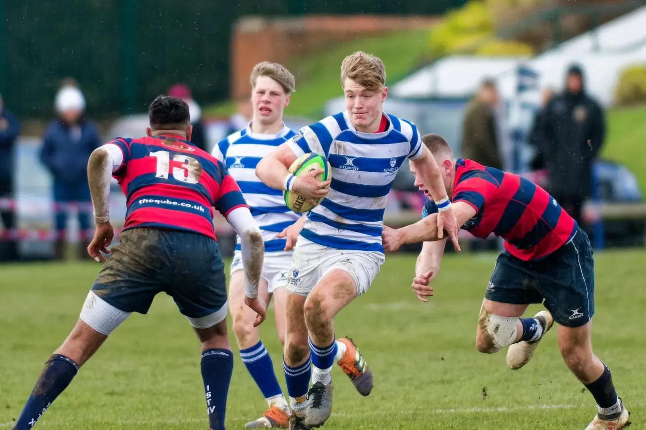 Rugby players competing on muddy pitch